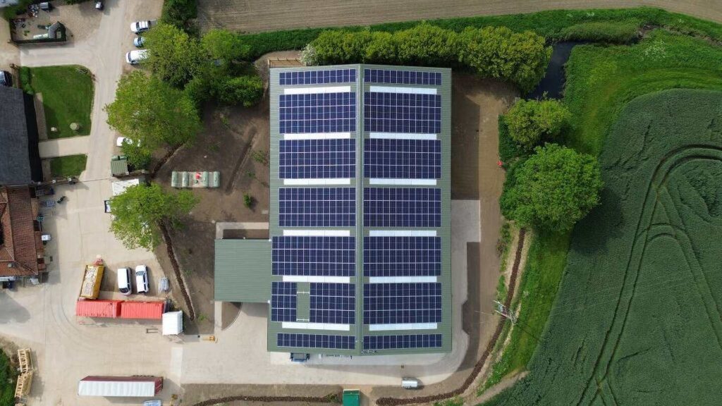 Roof mounted solar panels on barn roof on farm surrounded by fields