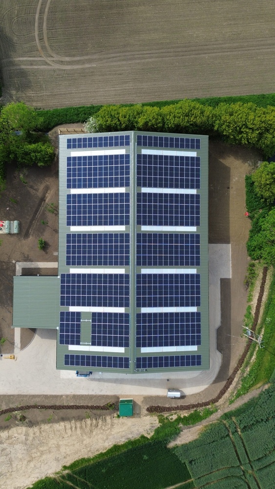 Roof mounted solar panels on barn roof on farm surrounded by fields